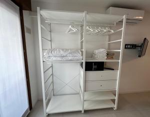 a white closet with white shelves and hangers at Residence Bristol Bibione in Bibione +6 photos