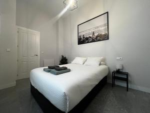 a bedroom with a white bed with a picture on the wall at Kadis-Korazon Grupo AC Gestion in Cádiz