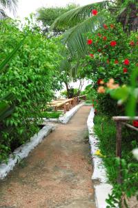 a garden with red flowers and a dirt road at Upendo Villa kewengwa in Kiwangwa