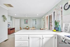 una cucina con armadi bianchi e una sala da pranzo di KozyGuru Glen Waverley Family Home & Backyard a Glen Waverley