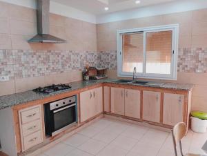 a kitchen with a stove and a sink and a window at Studio LINA in Hennchir Ksar Rhaleb