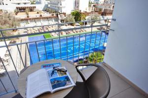 un balcone con un tavolo con un libro e una piscina di Hotel Puchet Ibiza a San Antonio Altre 115 foto