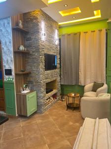 a living room with a tv and a stone fireplace at Vintage Green House in Fez