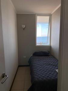 a small bedroom with a bed and a window at Departamento frente al mar full equipado in Coquimbo