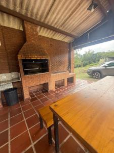 a patio with a brick fireplace and a wooden table at Casa de campo em São Roque in São Roque