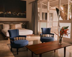 a bedroom with a bed and two chairs and a table at Kara Fort Kochi in Fort Kochi