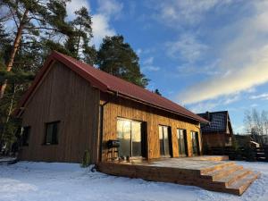 a log cabin with a deck in the snow at Przystanek Beztroska in Wydminy