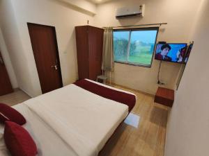 a bedroom with a bed and a window and a tv at Hotel Sandesh Palace Lonavala in Lonavala