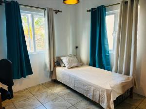 a small bed in a room with blue curtains at Cosy duplex in Res les Barachois 3,Grand-Gaube in Grand Gaube