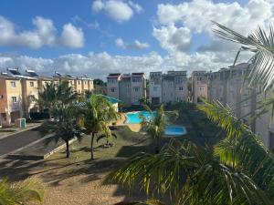 an apartment complex with a swimming pool and palm trees at Cosy duplex in Res les Barachois 3,Grand-Gaube in Grand Gaube