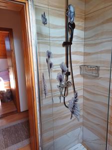 a shower with purple flowers and butterflies on the wall at Apartments Renata in Smoljanac