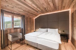 a bedroom with a large white bed and a window at Stay COOPER I DIAMANTIDI Lodge - Modern Mountain Chalet in the Dolomites in Obereggen