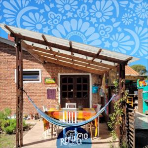 una pérgola de madera con una mesa frente a una casa en El Refugio, en Miramar