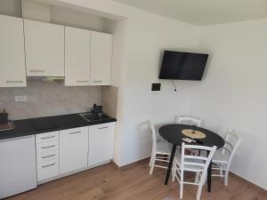 a kitchen with white cabinets and a table with chairs at Studio Apartma KIMI in Nova Gorica
