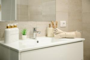 een wastafel in de badkamer met een fles zeep en andere artikelen bij Home2Rest at Los Gigantes - 1 min to beach, restaurants, city center - 1bdr in Acantilado de los Gigantes +30 foto's