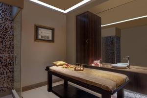ein Badezimmer mit einem Bett, einem Waschbecken und einem Spiegel in der Unterkunft Surat Marriott Hotel in Surat
