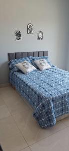 un letto con piumone e cuscini blu sopra di Loft 3M ad Arraial do Cabo