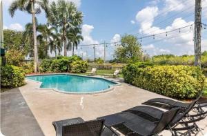 a resort style swimming pool with chairs and trees at Gardens Get Away in Pembroke Pines