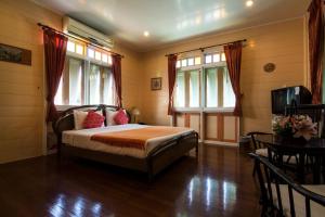 1 dormitorio con 1 cama, TV y ventanas en Samsen Sam Place, en Bangkok