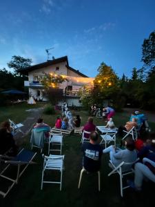 a group of people sitting in lawn chairs in front of a building at Inny Dom in Łacha