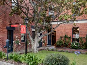 a brick building with a tree in the front yard at Montacute Boutique Bunkhouse in Hobart