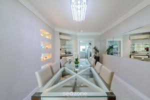 a dining room with a glass table and white chairs at Apto c vista mar privilegiada 4qts c suíte ETL2702 in Balneário Camboriú