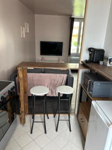 Una cocina con dos taburetes y una mesa con televisión. en Studio indépendant, en Saint-Éloi