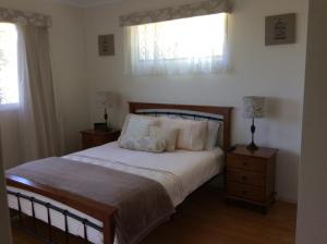 a bedroom with a bed with two night stands and two windows at Tinaroo Sunset Retreat in Barrine