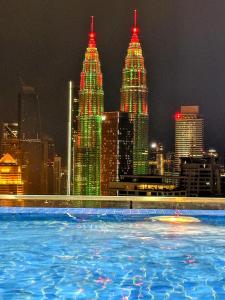 a pool in front of a city skyline at night at THE LUXE INFINITUM RESIDENCE at KL CITY in Kuala Lumpur