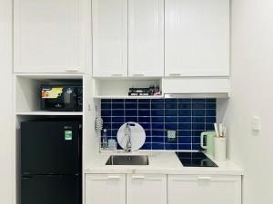 a kitchen with a sink and a black refrigerator at Love & Peace Apartment in Phú Quốc