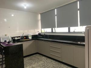 a kitchen with white cabinets and a large window at LK Lourdes 7 in Belo Horizonte