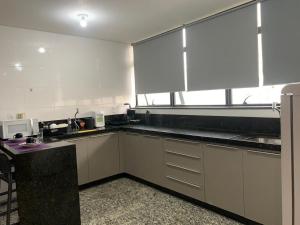 a kitchen with white cabinets and a large window at LK Lourdes 7 in Belo Horizonte