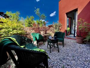 un patio avec des chaises et une table et un bâtiment dans l'établissement Les Terres Rouges du Salagou, à Le Bosc