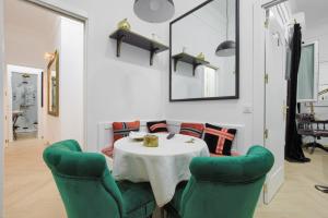 une salle à manger avec une table et deux chaises vertes dans l'établissement Salamanca Luxury Rooms, à Madrid