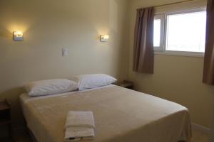 a bedroom with a bed with white sheets and a window at La hora azul departamentos in Playas Doradas