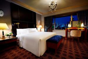 a bedroom with a large bed and a desk and a window at The Westin Osaka in Osaka