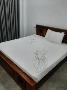 Una cama con sábanas blancas y almohadas. en Kusum Family House, en Dikwella