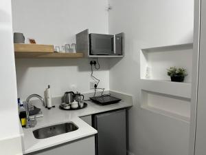 a small kitchen with a sink and a microwave at The Noble Lodge in Cape Town