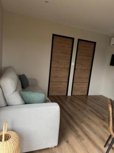 a living room with a white couch and two doors at studio Avec piscine et Spa Privatif Extérieur 4 personnes in Lestrem