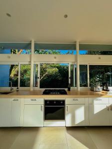a kitchen with white appliances and large windows at Ocean View Villa 2min to beach - Casa Cantini in Montezuma