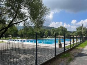 a fence in front of a swimming pool at Chata pod lasem z balią i sauną in Myślenice