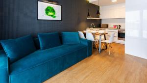 a living room with a blue couch and a kitchen at VacationClub - Baltin Apartament 21 in Mielenko