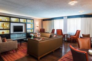 a living room with a couch and a tv and chairs at Sheraton Charlotte Airport in Charlotte