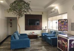 ein Wohnzimmer mit blauen Sofas und einem Fernseher in der Unterkunft Hotel Ceolatto Palace - Aeroporto in Várzea Grande