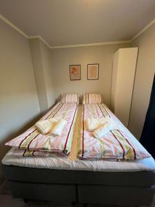 a bed with striped sheets and pillows in a bedroom at cozy room in Tromsø in Tromsø