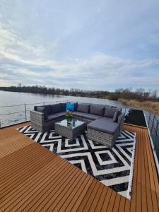 a deck with a couch and a table on a boat at Wasserbungalow Merlin in Lehnin