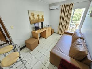 a living room with a couch and a tv and a table at Thermas Paradise - Apto de 1 quarto Vista área de lazer - 216 in Rio Quente +14 photos