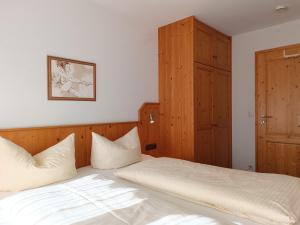 a bedroom with a bed and a wooden cabinet at 2-Raum FeWo Alpenveilchen - Hallenbad & Sauna in Fischen +7 photos