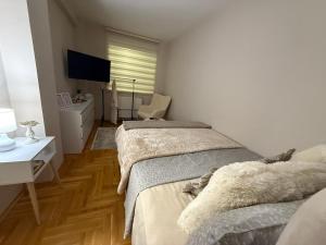 a bedroom with two beds and a desk and a television at Urban Apartman-privatan parking- in Kraljevo
