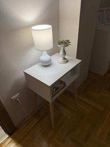 a white table with a lamp on top of it at Urban Apartman-privatan parking- in Kraljevo